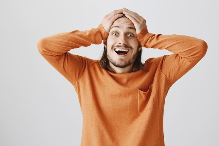 Foto gratuito el hombre emocionado feliz reacciona a las noticias maravillosas, se toma las manos en la cabeza asombrado