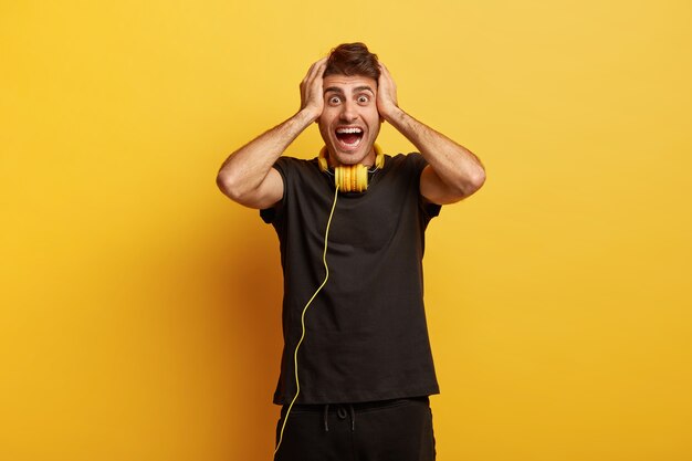 El hombre emocionado feliz y sorprendido mantiene las manos en la cabeza, tiene los ojos saltones y los ojos bien abiertos, no puede creer en algo sorprendente