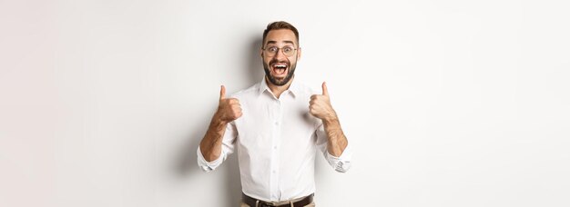 Hombre emocionado con gafas que muestra los pulgares hacia arriba y se ve asombrado de acuerdo y aprueba algo genial recomendado