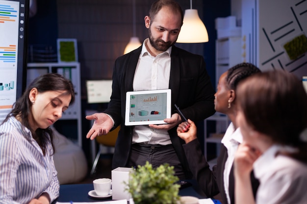 Foto gratuita hombre emprendedor adicto al trabajo enfocado trabajando horas extras presentando estadísticas de la empresa