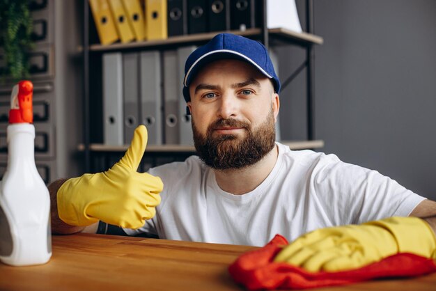 Hombre de la empresa de limpieza limpiando usando guantes de goma y usando spray