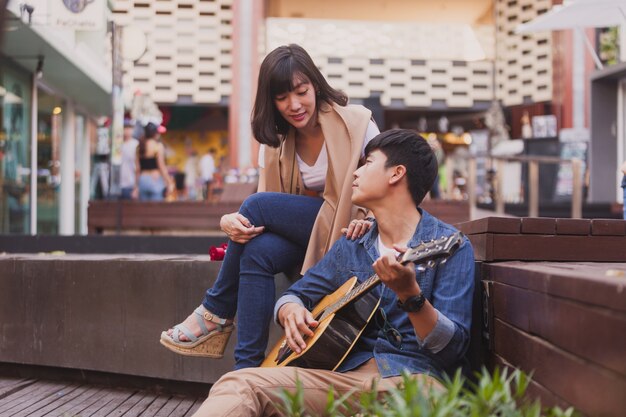 Hombre enamorado tocando la guitarra sentado en el suelo a su novia