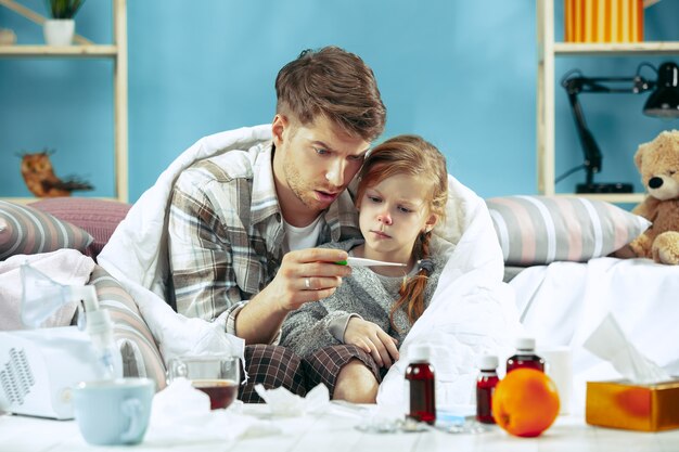 Hombre enfermo con hija en casa. Tratamiento a domicilio. Luchando con una enfermedad. Asistencia médica. Iilidad familiar. El invierno, la gripe, la salud, el dolor, la paternidad, el concepto de relación. Relajación en casa