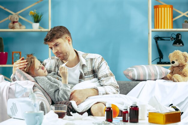 Hombre enfermo con hija en casa. Tratamiento a domicilio. Luchando con una enfermedad. Asistencia médica. Iilidad familiar. El invierno, la gripe, la salud, el dolor, la paternidad, el concepto de relación. Relajación en casa