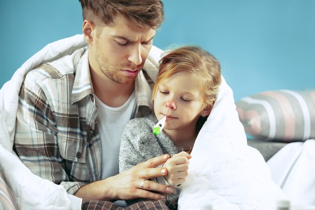 Hombre enfermo con hija en casa. Tratamiento en el hogar. Luchando con una enfermedad. Asistencia médica. Debilidad familiar. El invierno, la influenza, la salud, el dolor, la paternidad, el concepto de relación. Relajación en casa