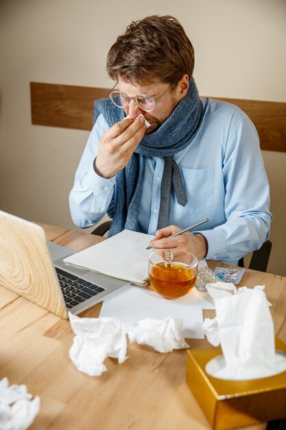 Hombre enfermo mientras trabajaba en la oficina, el empresario se resfrió, gripe estacional.