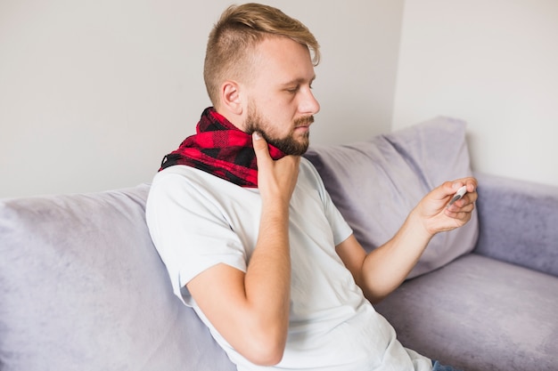 Hombre enfermo que sostiene la mano en el cuello