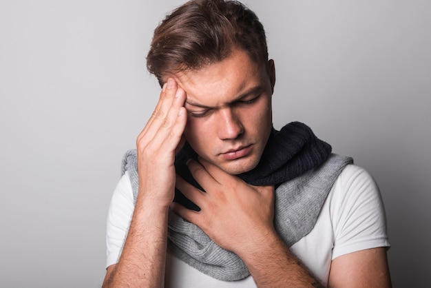 Foto gratuita hombre enfermo que sufre de dolor de cabeza y frío contra el fondo gris