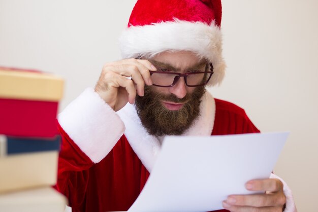 Hombre enfocado con traje de Santa y documento de lectura