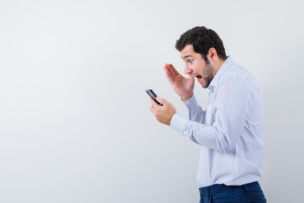 Hombre enojado mirando su teléfono sobre fondo blanco.