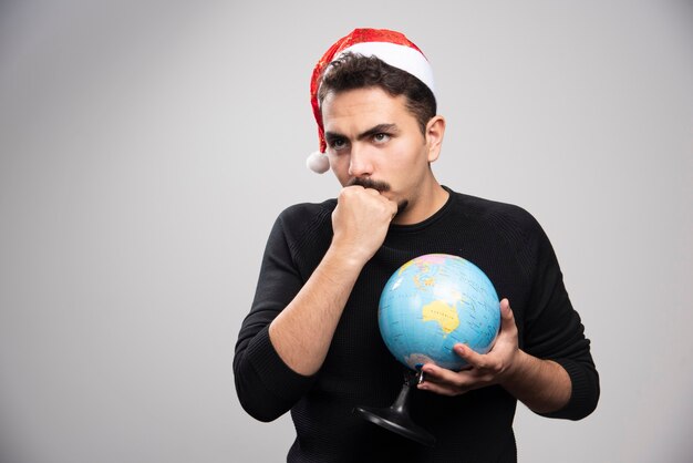 Hombre enojado con sombrero de Santa mostrando un puño y sosteniendo un globo.