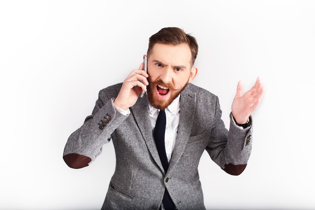 Hombre enojado en traje gris habla por teléfono