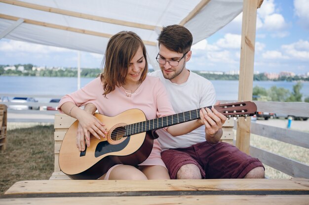 Hombre enseñando a tocar la guitarra a una chica