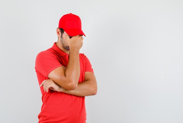 Hombre de entrega con la mano en la cara en camiseta roja