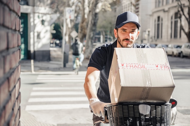 Hombre de entrega montando bicicleta con paquete