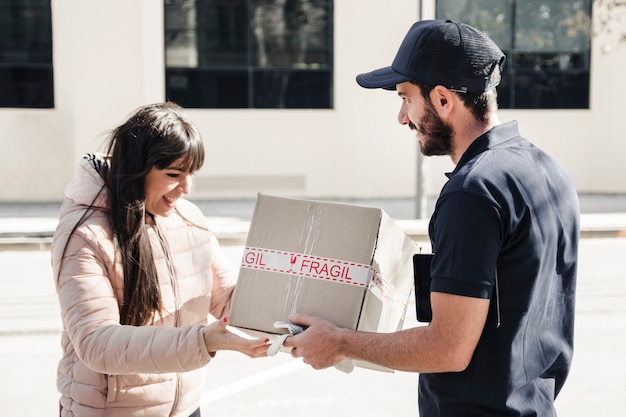 Hombre de entrega que entrega el paquete al cliente femenino