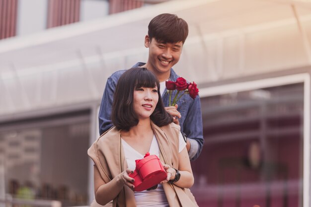 Hombre entregando un regalo y rosas a una mujer