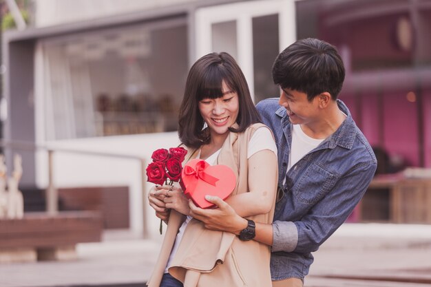 Hombre entregando un regalo y rosas a una mujer