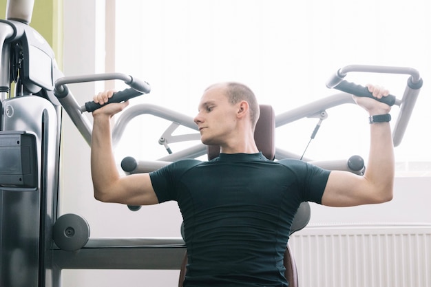 Hombre de entrenamiento con simulador en el gimnasio