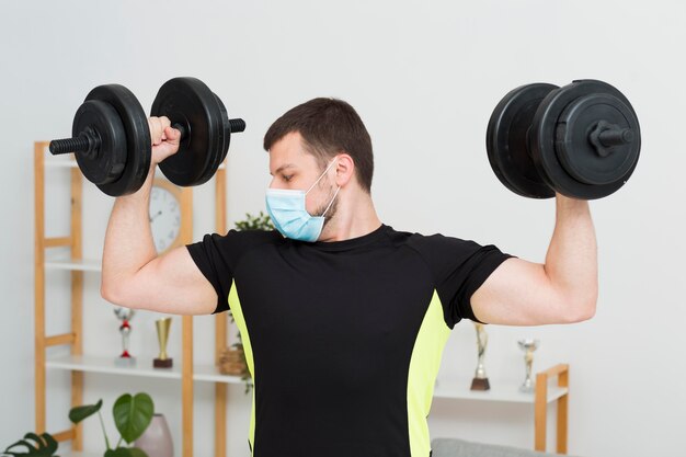 Hombre entrenando en casa usando una máscara médica