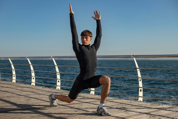 Hombre entrenando en ropa deportiva en la playa.