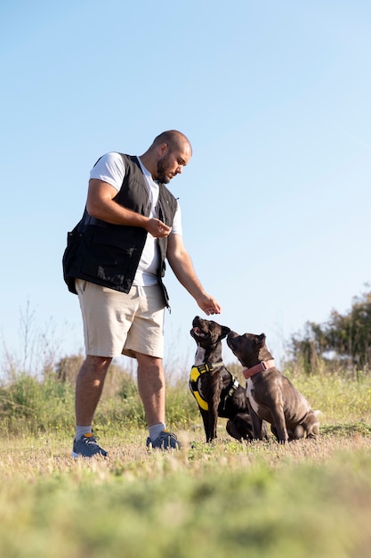 Hombre entrenando a sus dos perros al aire libre