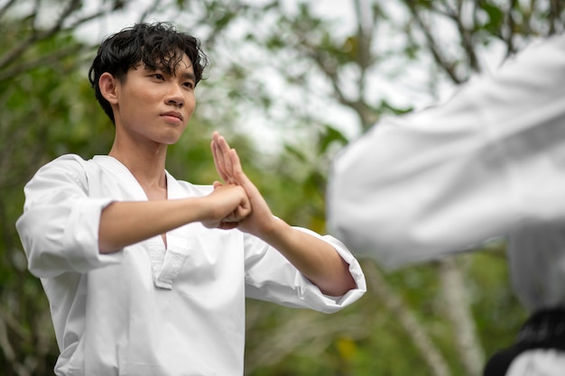 Foto gratuita hombre entrenando en taekwondo al aire libre en la naturaleza