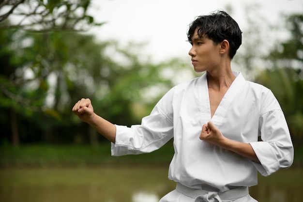 Foto gratuita hombre entrenando en taekwondo al aire libre en la naturaleza
