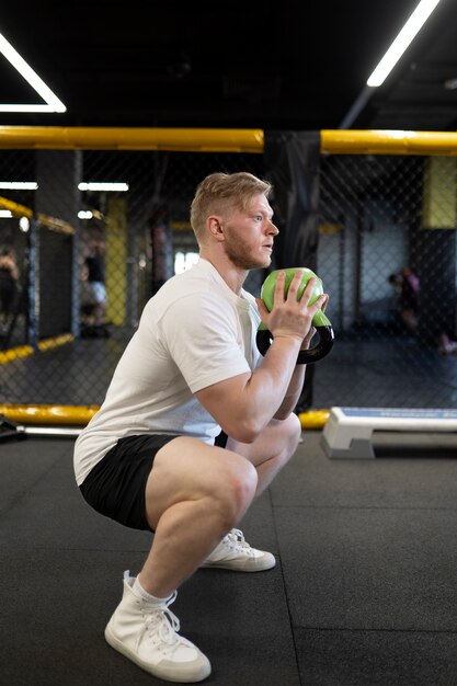 Hombre entrenando con tiro completo de pesas rusas verdes