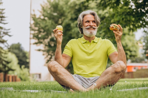 Hombre envejecido eligiendo entre hamburguesa y manzana