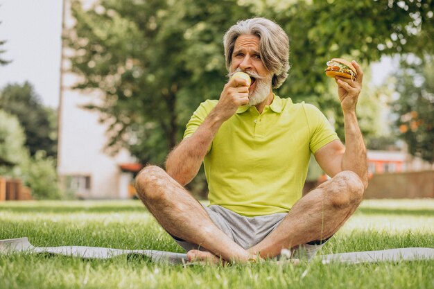 Hombre envejecido eligiendo entre hamburguesa y manzana