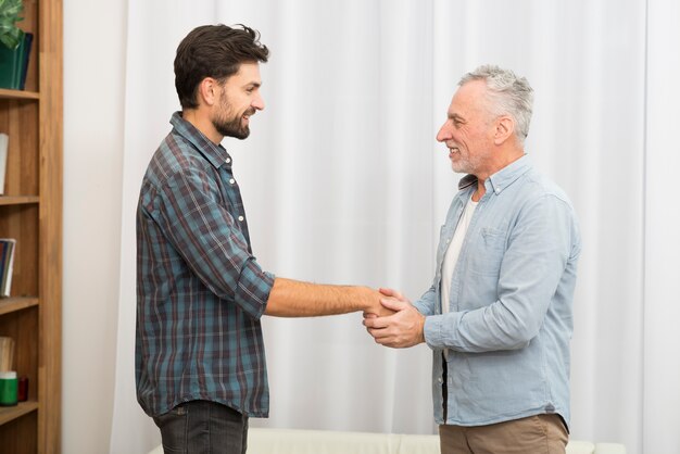 Hombre envejecido que lleva a cabo las manos del chico feliz joven