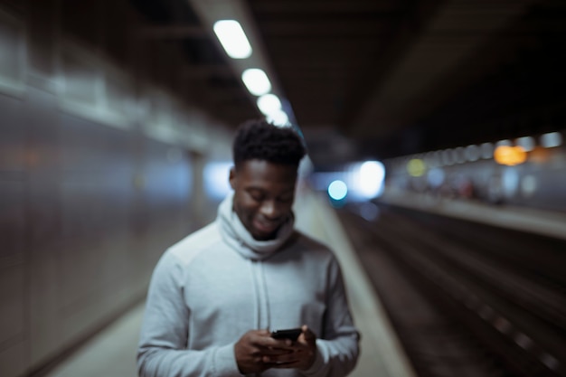 Hombre enviando mensajes de texto en una estación de metro