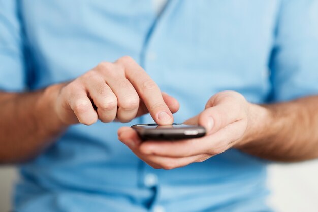 Hombre enviando mensajes de texto por teléfono móvil