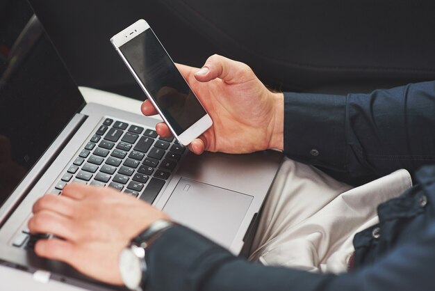 El hombre es un hombre que trabaja en una computadora portátil y prueba en dispositivos móviles.