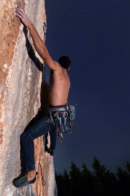 Hombre escalando una montaña con equipo de seguridad