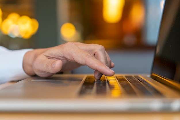 Hombre escribiendo en la computadora portátil con bokeh