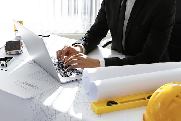 Hombre escribiendo en la computadora portátil junto a herramientas de ingeniería