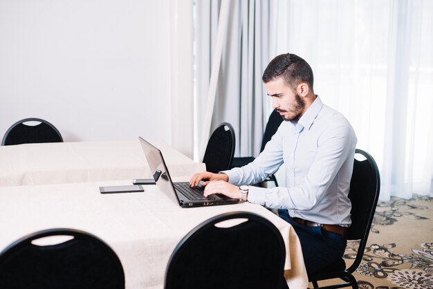 Hombre escribiendo en la computadora portátil en la oficina
