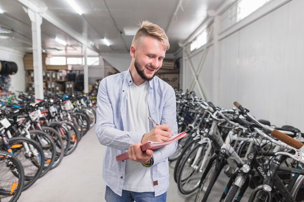 Hombre escribiendo en el documento en la tienda de bicicletas