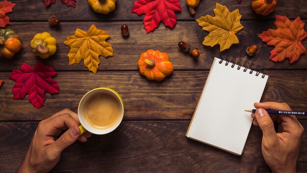 Hombre escribiendo en otoño decorado lugar de trabajo