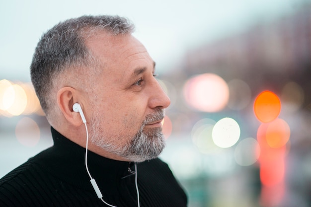 Hombre escuchando música afuera con espacio de copia