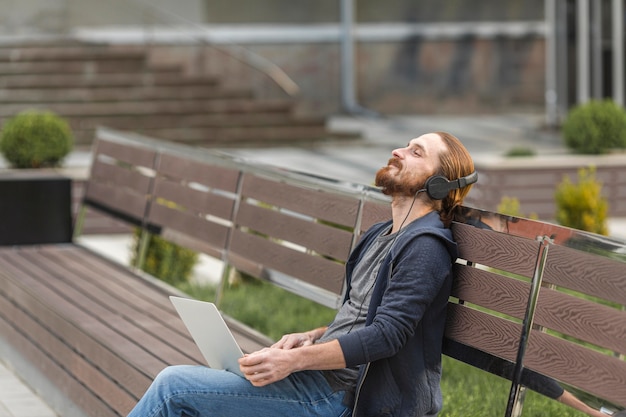 Hombre escuchando música con auriculares al aire libre en la ciudad