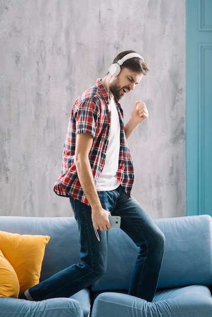 Hombre escuchando música y bailando en el sofá