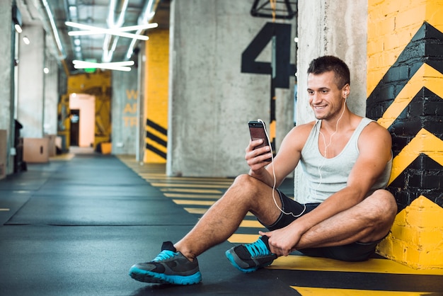 Hombre escuchando música en celular en el gimnasio