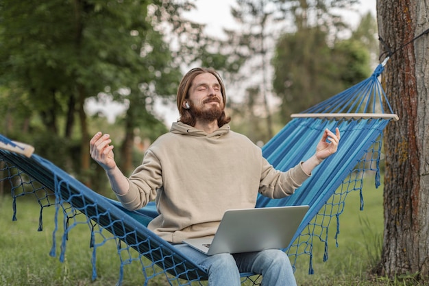 Hombre escuchando música zen mientras está sentado en la hamaca