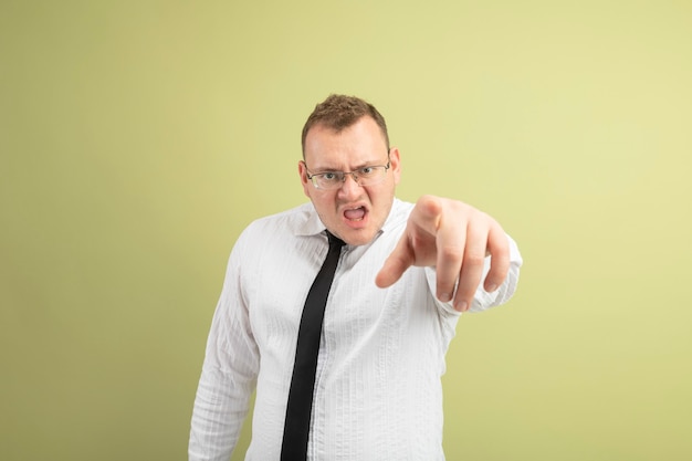 Foto gratuita hombre eslavo adulto con el ceño fruncido con gafas y corbata mirando y apuntando a la cámara aislada sobre fondo verde oliva con espacio de copia