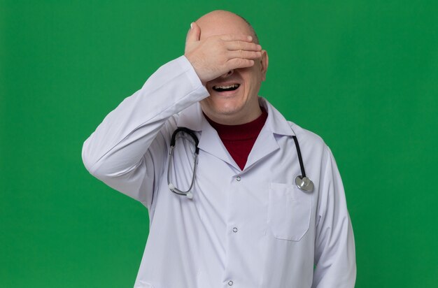 Hombre eslavo adulto decepcionado en uniforme médico con estetoscopio poniendo la mano en la frente