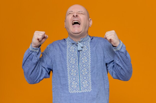 Hombre eslavo adulto emocionado en camisa azul manteniendo los puños