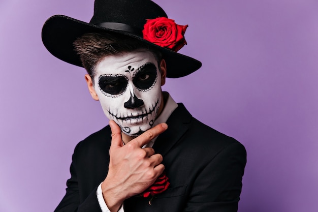 Hombre español pensativo con sombrero negro de ala ancha con mirada seria posando en traje para Halloween.